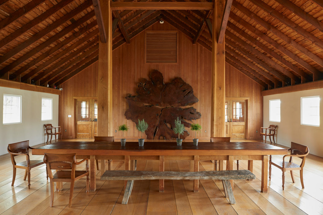 Long wooden dining table in a wood paneled room with arched ceiling.
