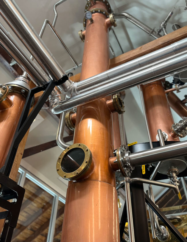 Long copper column in a distillery room.
